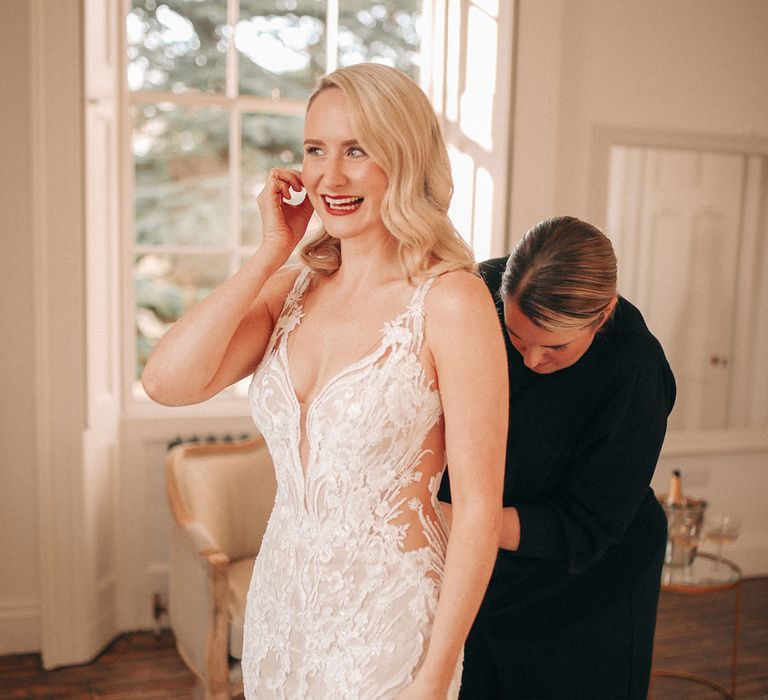 Bride steps into her fitted lace wedding dress at classic winter wedding 