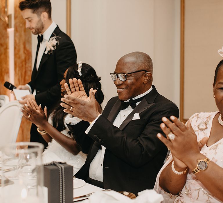 Parents of the groom at the wedding top table laughing along to the wedding speeches 