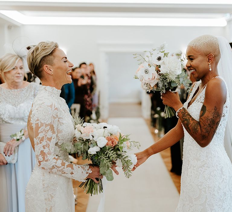 Two brides holding hands at their same sex wedding ceremony 