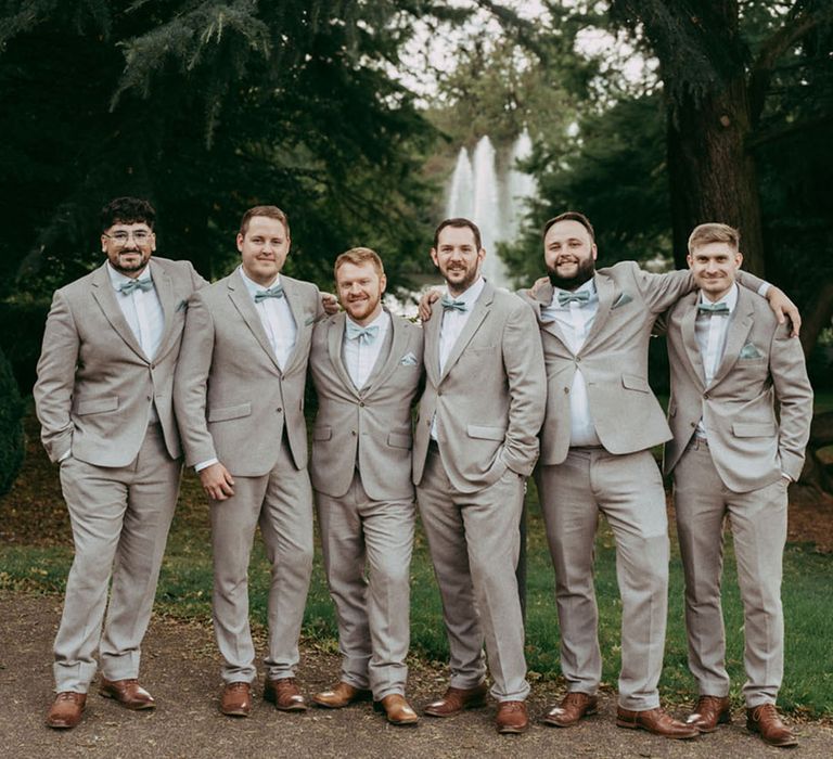 The groom and groomsmen in grey suits with matching green bow ties at the Lord of The Rings theme wedding 