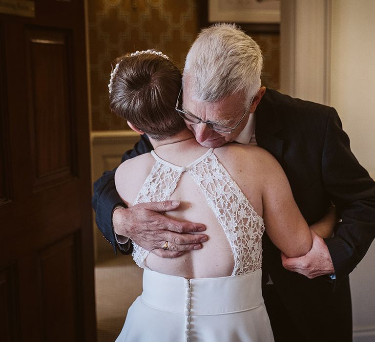 Father of the bride embraces the bride in the first look reveal at country house wedding