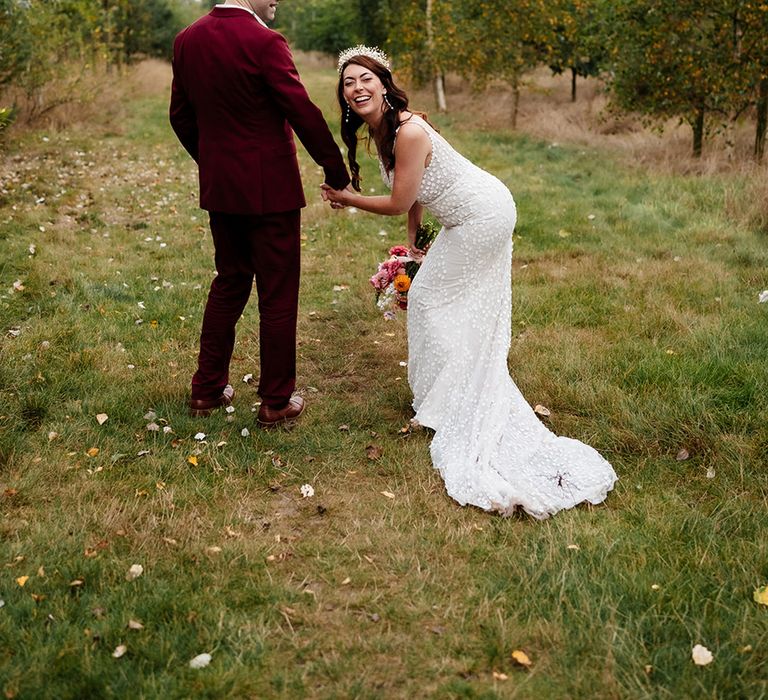 Groom in burgundy wedding suit with the bride in patterned wedding dress from Made With Love Bridal 