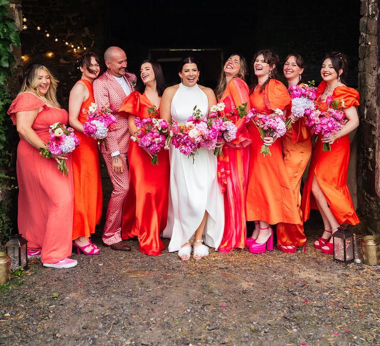 Bright vibrant orange bridesmaid dresses and suit for the bridal party wearing hot pink shoes