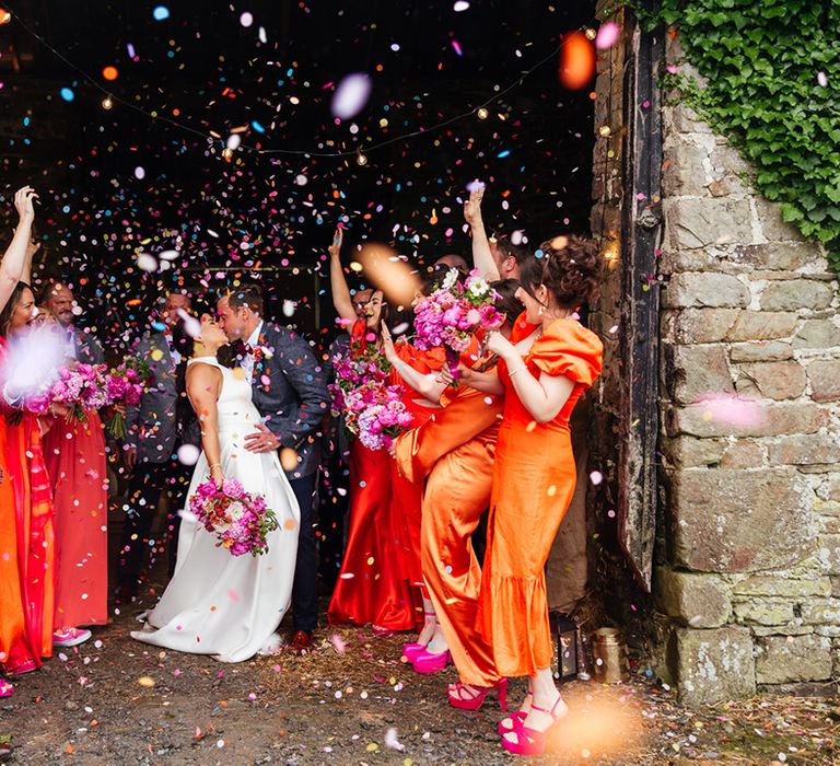 Colourful vibrant confetti moment for bride and groom with their wedding party 