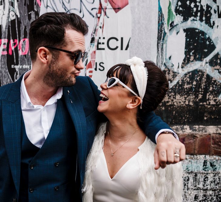 Stylish bride and groom in sunglasses looking at each other 