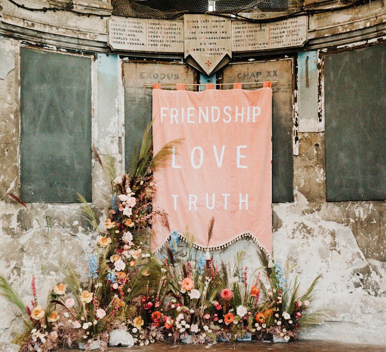 Pink fabric wedding sign and colourful flowers decorating the industrial wedding venue altar 