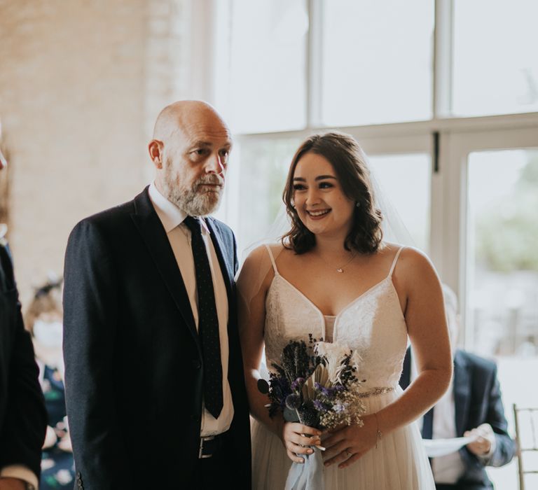 Smiling bride with father at the altar