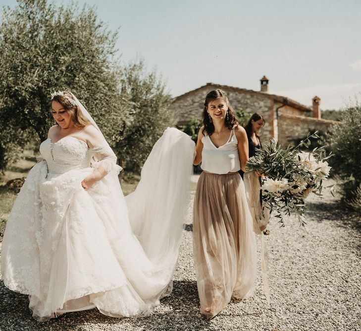 Bridesmaid helping Bride with her dress and olive bouquet