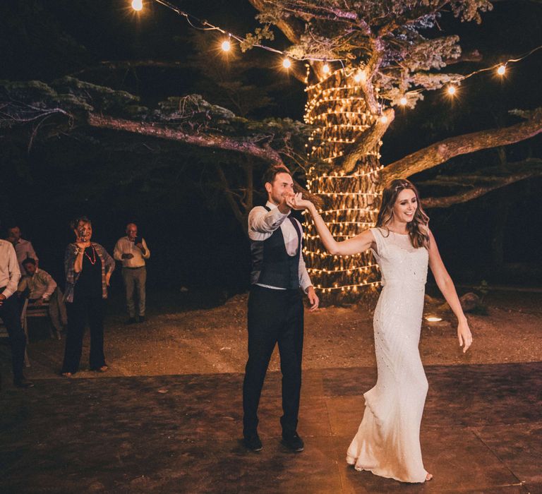 Newly-wed couples first dance by festoon light lit tree in Tuscany Italy