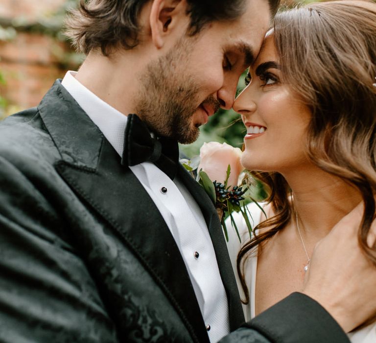 Close-up wedding day photography of bride and groom with pink rose and beaded hair bridal hair accessory 