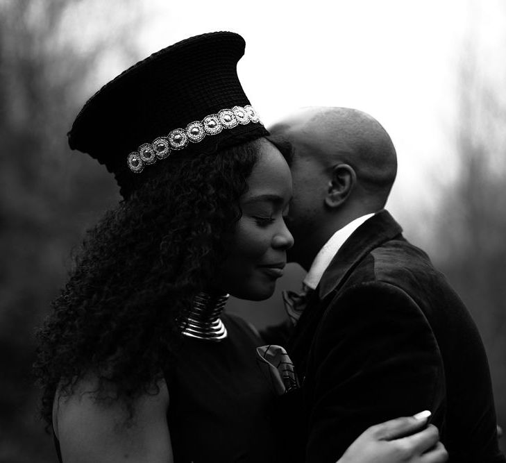 Groom kissing his bride wearing a Ndebele and Zulu hat 