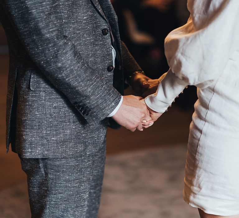 Bride and groom holding hands with bride wearing a short wedding dress