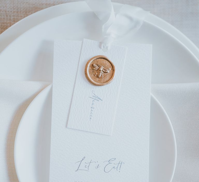 Place setting and menu cards tied with ribbon and decorated with a gold was seal