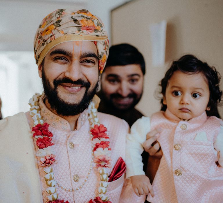 Grooms arrives wearing floral turban and pastel pink outfit