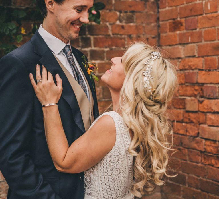 Bride in Justin Alexander wedding dress and pearl headband smiles up at Groom in navy suit and beige waistcoat at Iscoyd Park wedding reception