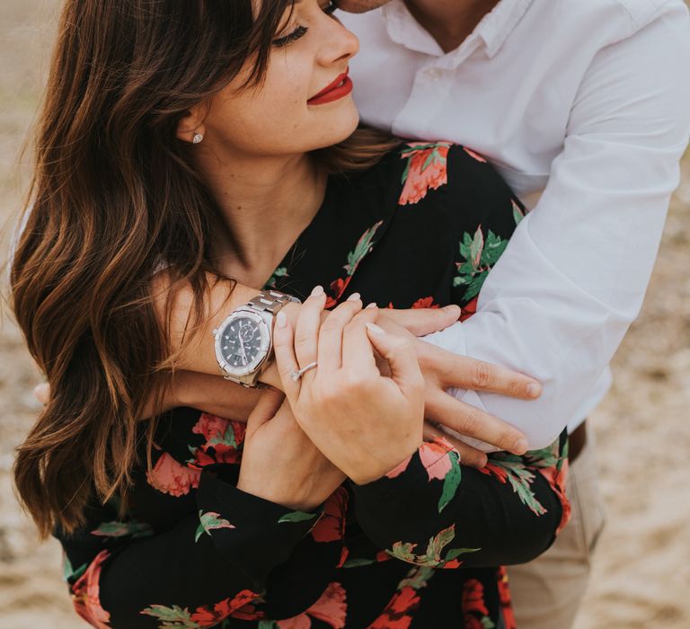 Groom-to-be in a white shirt kissing his bride-to-be's forehead on the beach during their engagement photo shoot