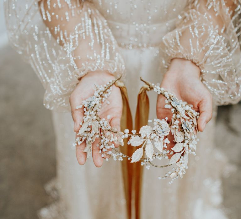 Bride holding a white and gold wedding floral hair accessory