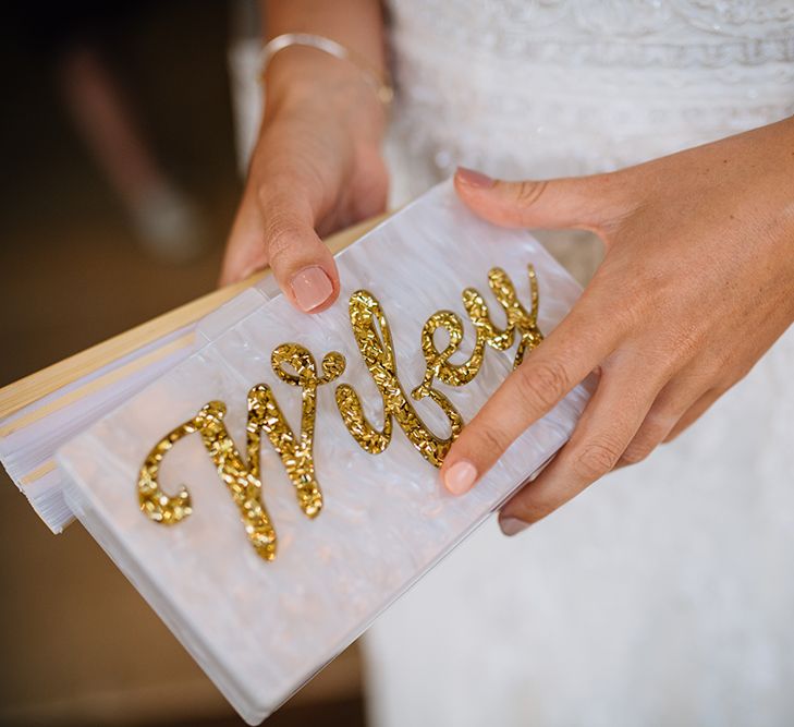 Bride holding gold and white wifey purse with peach wedding nails