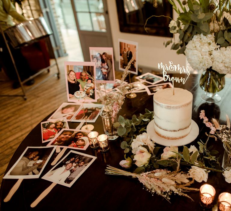 Cake display table with semi naked wedding cake, and polaroid pictures decor 