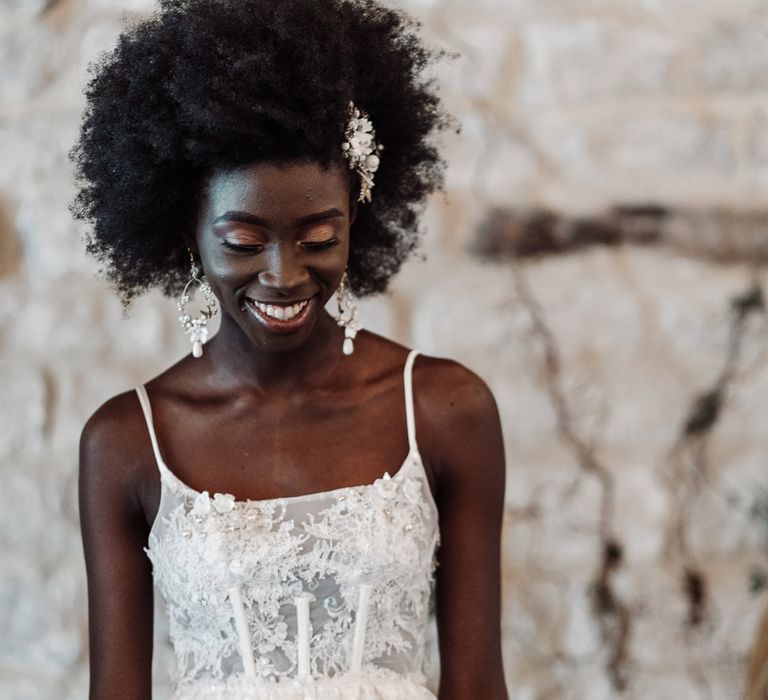 Black bride with afro hair smiling in a lace peplum wedding dress with boned bodice and fitted skirt 