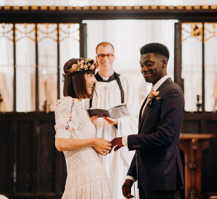 Bride in a laser cut and embroidery wedding dress putting on her grooms wedding ring 