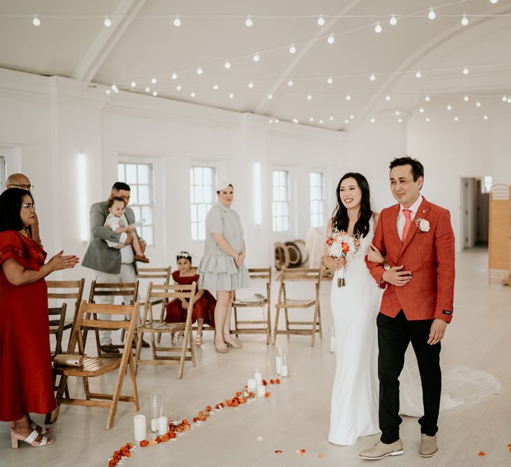 Minimalist wedding at Core laptop with petals, bamboo screens and pillar candles lining the aisle as the father of the bride walks his daughter down