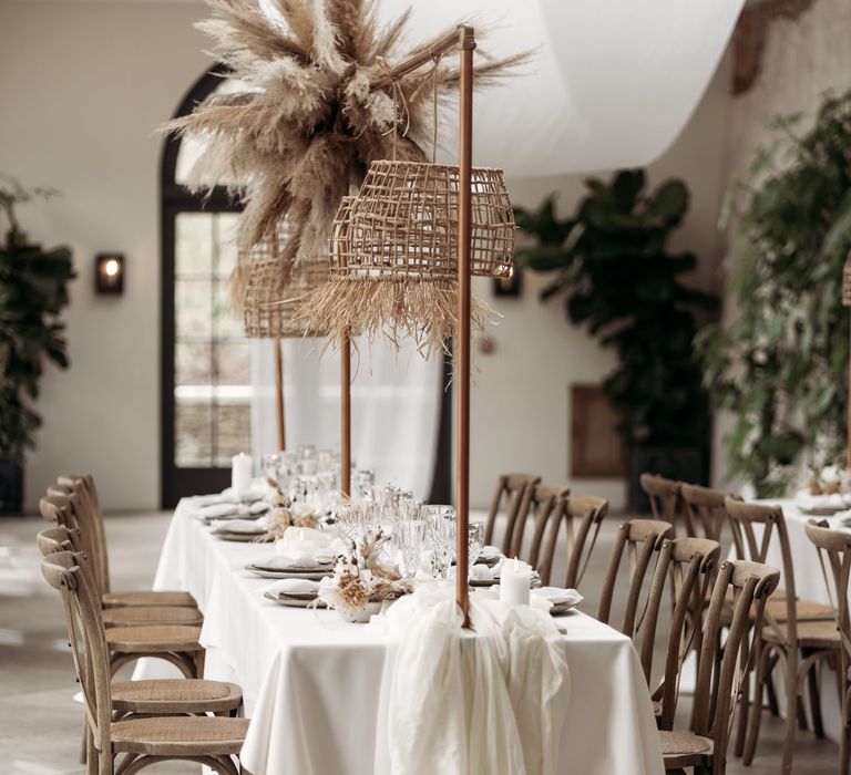 Wooden table and chairs with drapes, pampas grass and wicker lampshades