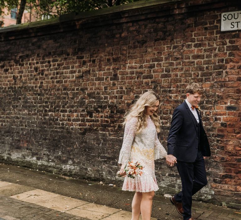 Bride and groom on their wedding day in Manchester holding hands