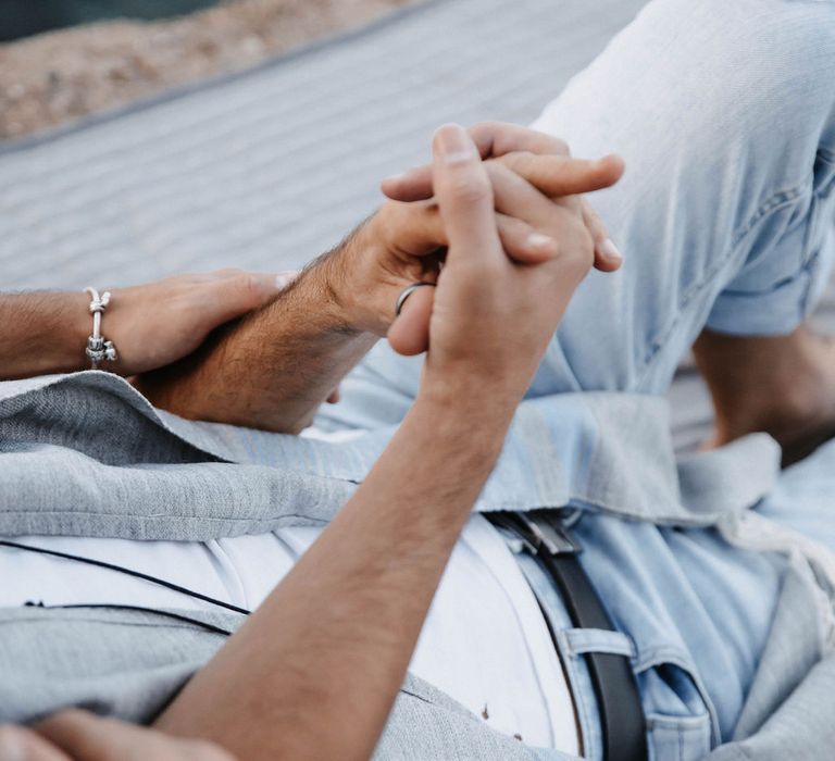 Close up image of grooms holding hands 