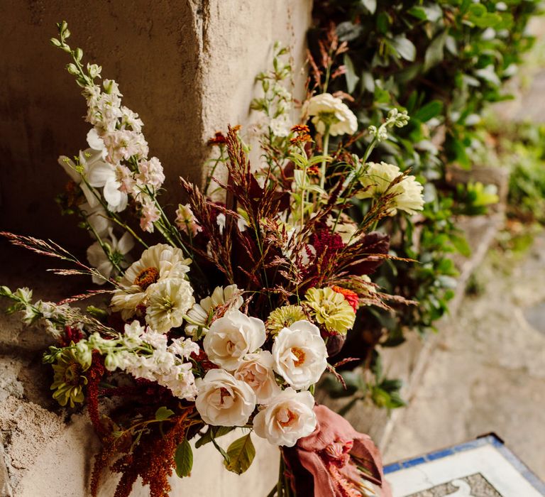 Bouquet of white wild roses, gerbera flowers and dark wild grasses