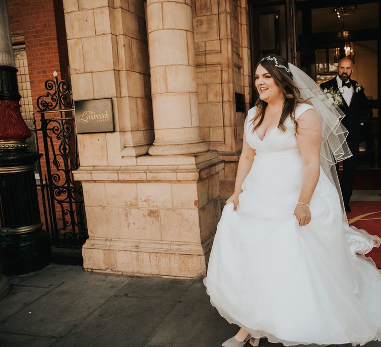 Bride lifts skirt of wedding dress from Wed2B and veil blows in the wind