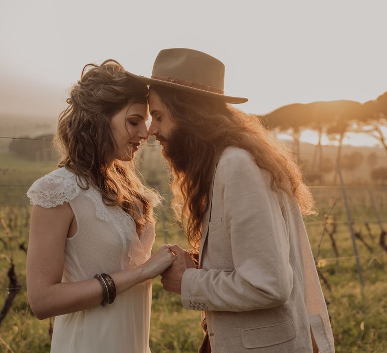 Bride & groom lean in to kiss one another during sunset in the Sicilian countryside for hippie wedding