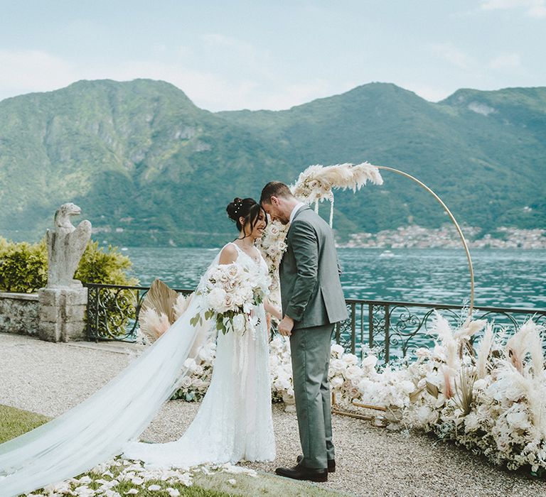 Bride & groom kiss one another outside during wedding ceremony in front of Lake Como