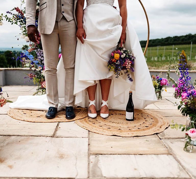 Bride and groom standing on wicker rugs at the outdoor wedding ceremony at Little Wold Vineyard