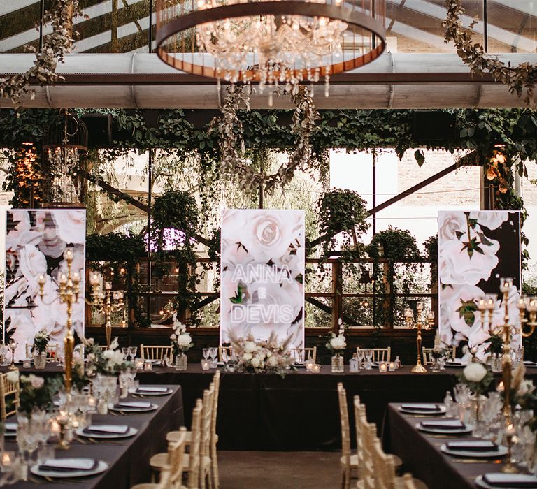 Hanging chandelier within rose gold birdcage above dark and gold colour schemed reception venue and LED lighting 