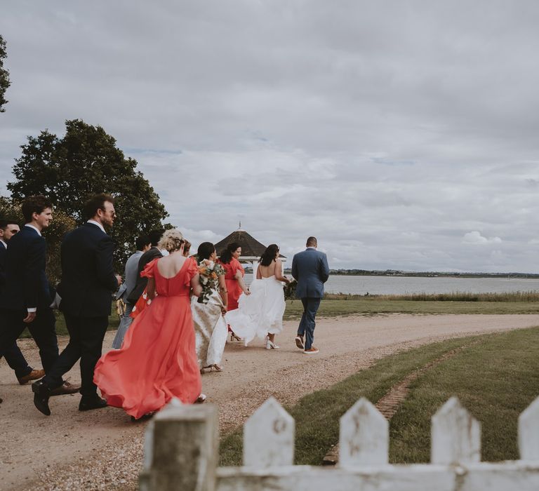 Bride and groom leading the wedding guests from along the coastal walk at Osea Island wedding 