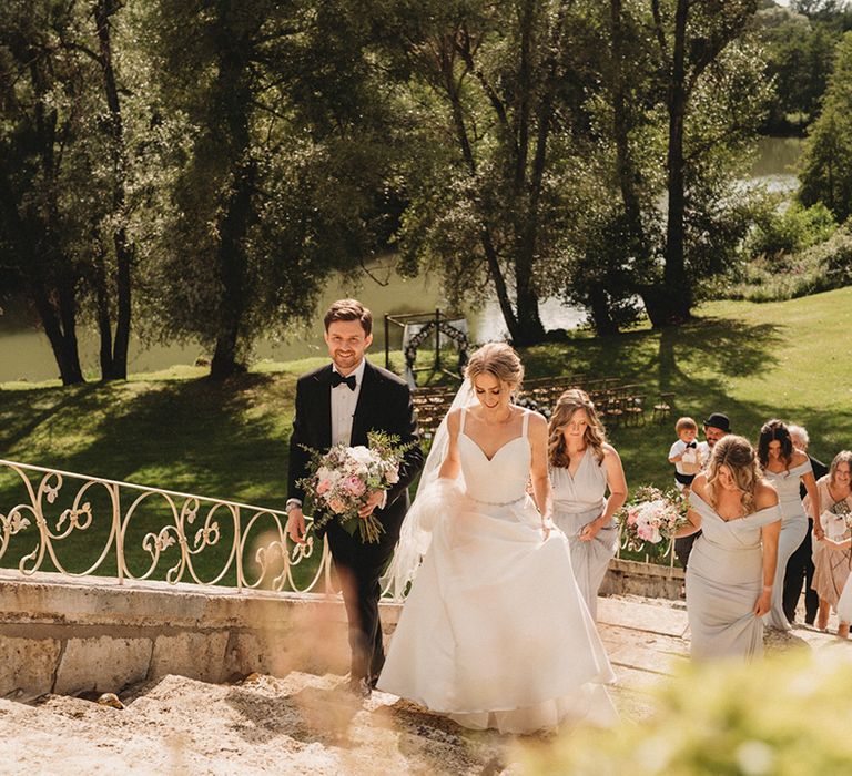 Bride and groom walking up the steps of Chateau Lagorce from their outdoor wedding ceremony in the gardens 