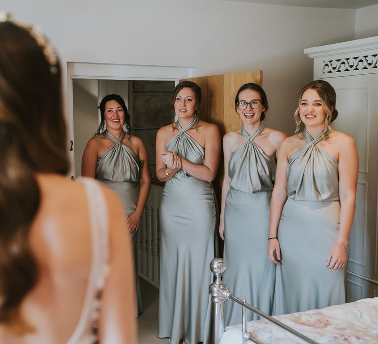 Bridesmaids in sage green satin halter neck bridesmaid dress have first look at the bride for summer wedding at Primrose Hill Farm