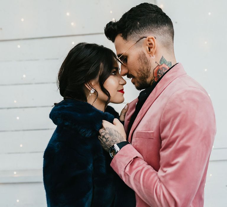 Intimate bride and groom portrait with the groom in a pink velvet jacket and the bride a navy blue faux fur bridal cover up 