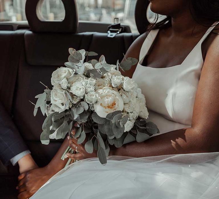 Bride holds white floral bouquet whilst wearing Whistles wedding gown