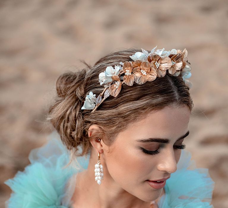 Bride with smokey eyeshadow, and natural lipstick wearing a gold flower headband and dangly earrings 