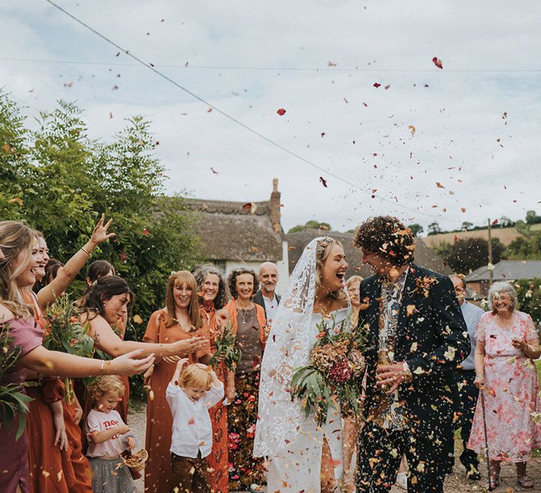 Bride & groom kiss as confetti is thrown around them