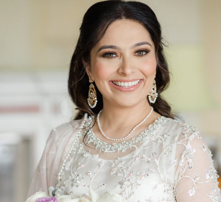 Indian bride holds pastel floral bridal bouquet and wears her dark hair long and in loose curls