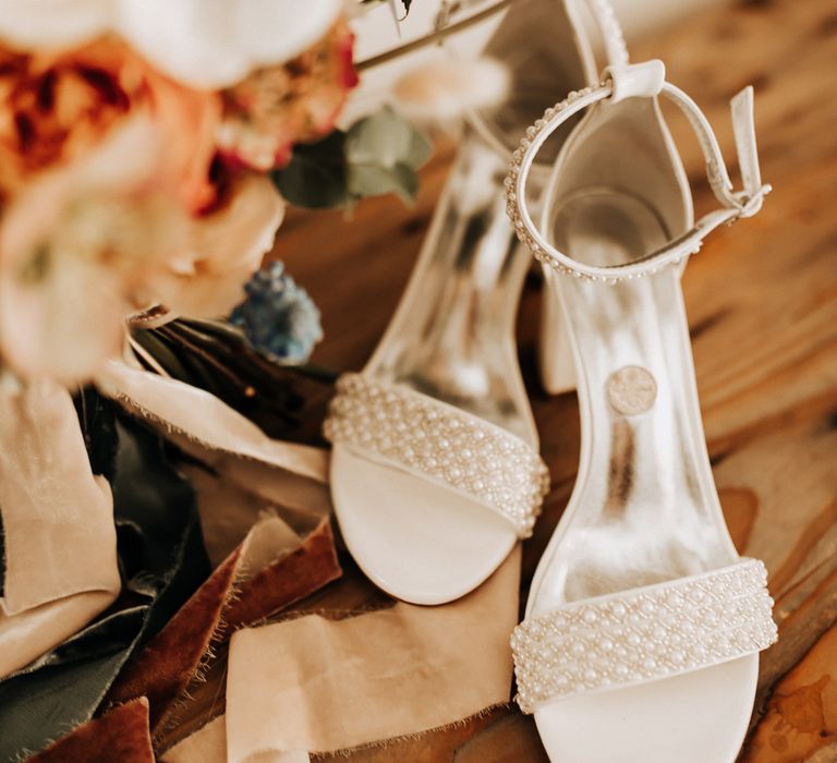 White bridal heels with pearl detailing next to pastel bridal bouquet