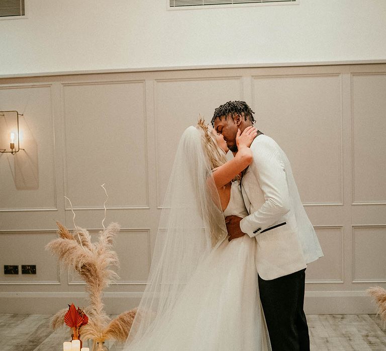 Bride and groom kiss in front of pampas grass wedding decor