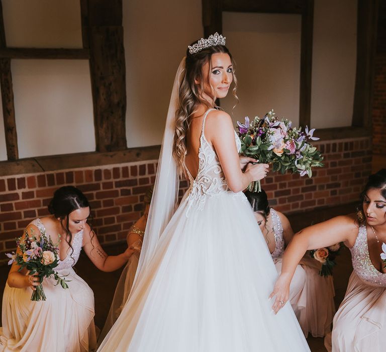 Bride in tulle skirt wedding dress with puddle train and veil with silver tiara and deep v-cut back 