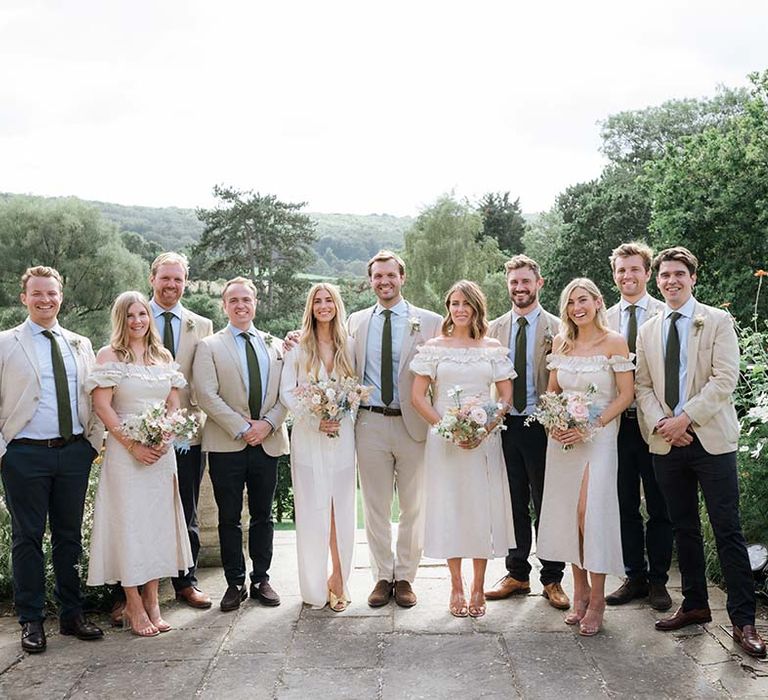 Bride and groom pose with their bridesmaids and groomsman with English countryside for a backdrop