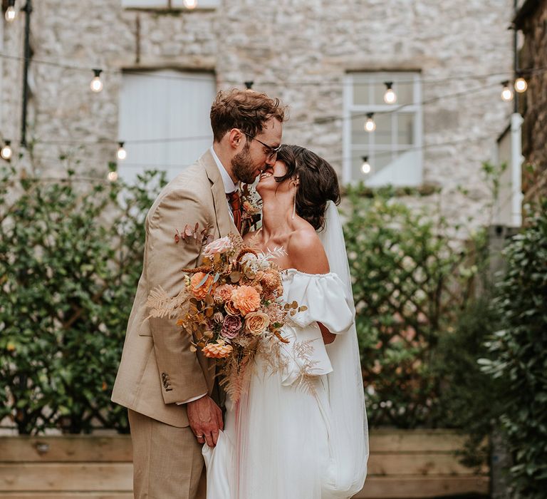 Bride and groom lean in for a kiss after their wedding ceremony at industrial wedding venue