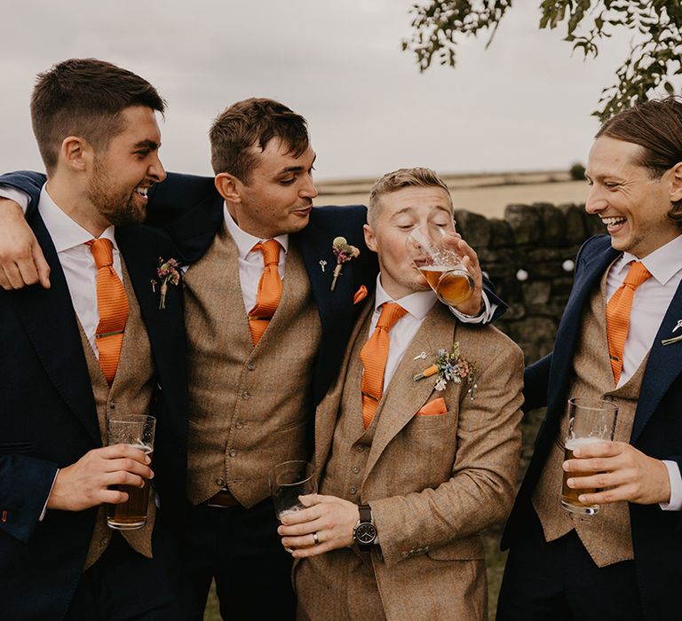 Groomsmen and the groom all stand together with their pints as the groom drink from his friends glass