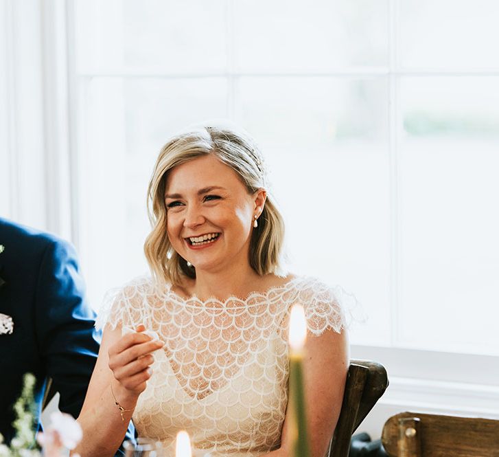 Bride wears scalloped lace top and laughs during wedding reception at Aswarby Rectory 